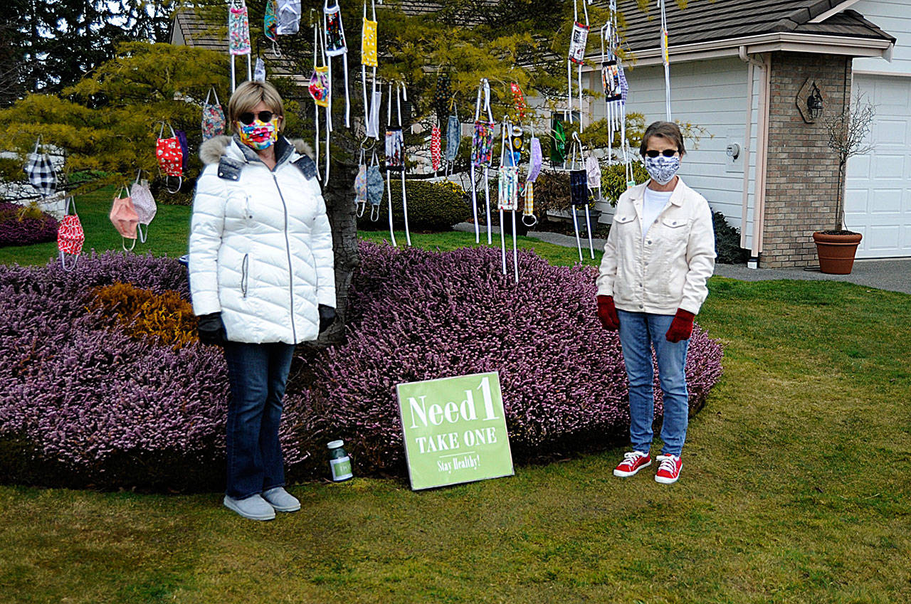 In Sunland North, Danette Bemis, left, and Kathy Tiedeman continue to hang cloth masks they make for free in Bemis’ front yard. Donations are accepted to help continue the effort, the friends said. Sequim Gazette photos by Matthew Nash