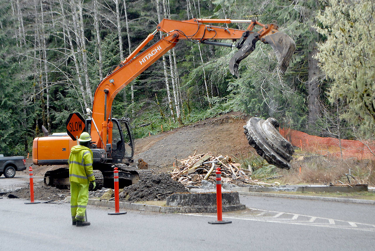 Jim Childs, a traffic control supervisor for Vancouver, Wa.,-based Conway Construction Co., watches as an excavator breaks up concrete at the site of the former Heart o’ the Hills entrance station to Olympic National Park on March 25, south of Port Angeles. Photo by Keith Thorpe/Olympic Peninsula News Group