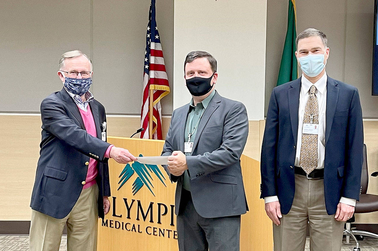 Bruce Skinner, Olympic Medical Center Foundation executive director (at left), presents a check for $55,000 at last week’s OMC Commissioner’s meeting to commission chair John Nutter, center, and OMC CEO Darryl Wolfe. Submitted photo