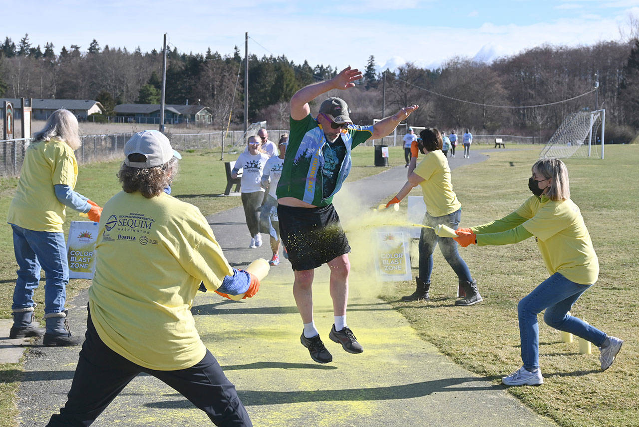Alex Baker of Port Angeles playfully tries to avoid doses of yellow — courtesy of volunteers from the Olympic Peninsula Visitors Bureau — at a color station near the end of the Sun Fun Color Run 5k on March 6. Sequim Gazette photo by Michael Dashiell