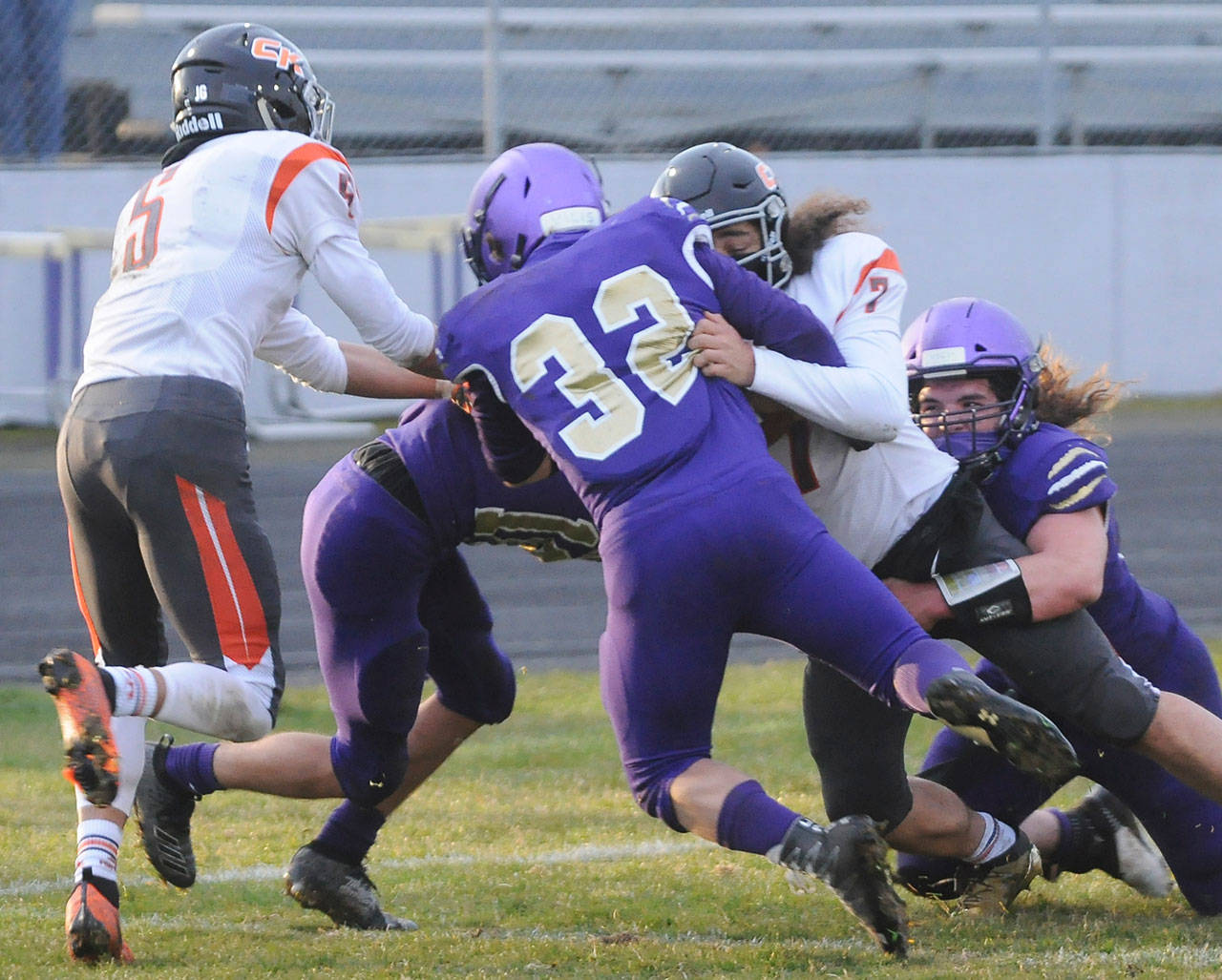 Sequim defenders Truman Nestor (center), Taig Wiker (right) and Garrett Hoesel (background) wrap up Central Kitsap quarterback Kalai Pasai in the first half of Sequim’s 38-22 win on March 18. Sequim had two key goalline stands against the Cougars. Sequim Gazette photo by Michael Dashiell