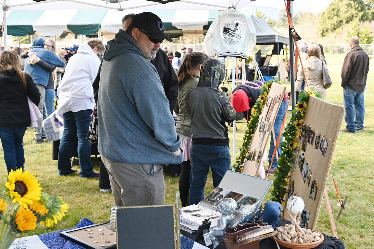 Mike McFarlen looks at photos and other pieces of family history of longtime Sequim youth sports volunteer Don Knapp. Family and friends held a memorial and Little League fundraiser on April 11 in honor of Knapp, who passed away in November 2020. Sequim Gazette photo by Michael Dashiell