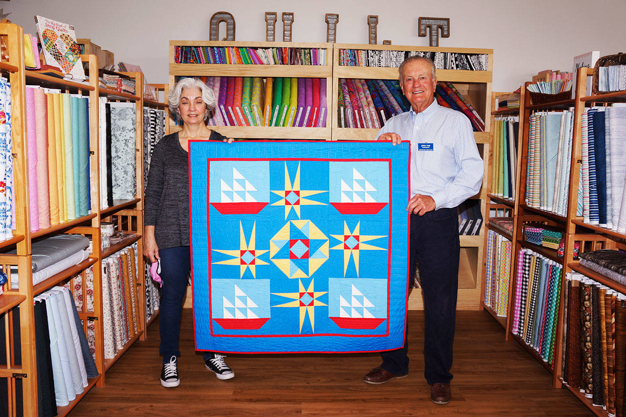 Quilt maker Dory Miller of Crazy Horse Quilting and Sequim Bay Yacht Club commodore Jerry Fine display a quilt up for raffle at A Stitch in Time Quilt Shoppe in Sequim. Proceeds go to Volunteer Hospice of Clallam County for respite care. Submitted photo