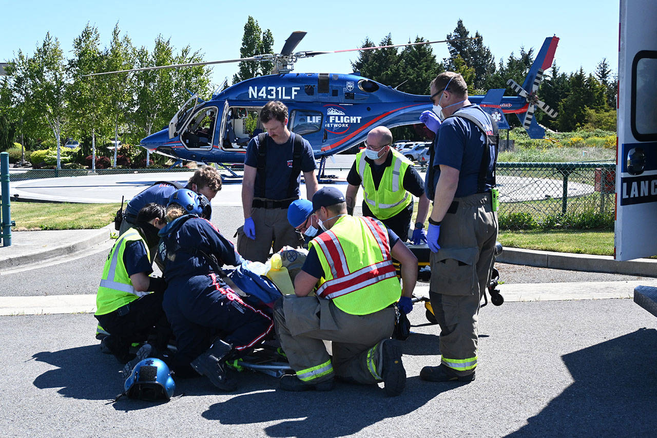 Personnel with Life Flight Network, Olympic Ambulance and Clallam County Fire District 3 secure a patient for transport Friday morning from a helipad in Sequim. The 69-year-old Port Angeles man was injured in a single car roll-over on U.S. Highway 101. Sequim Gazette photo by Michael Dashiell