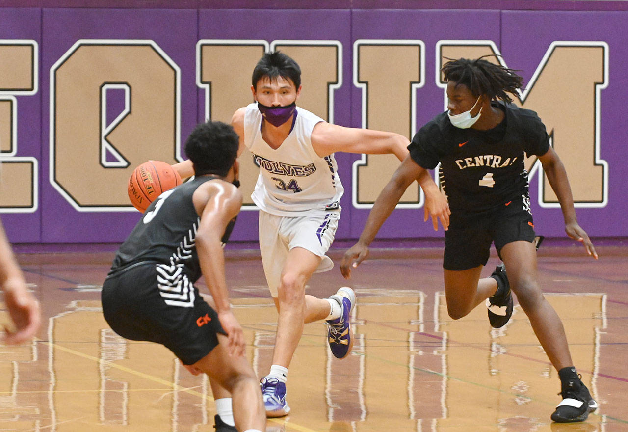 Sequim’s Isaiah Moore brings the ball upcourt in the second half of the Wolves’ 72-49 loss to Central Kitsap on June 2. Defending on the play are Darnell Green, left, and Jo Jo Johnson. Sequim Gazette photo by Michael Dashiell