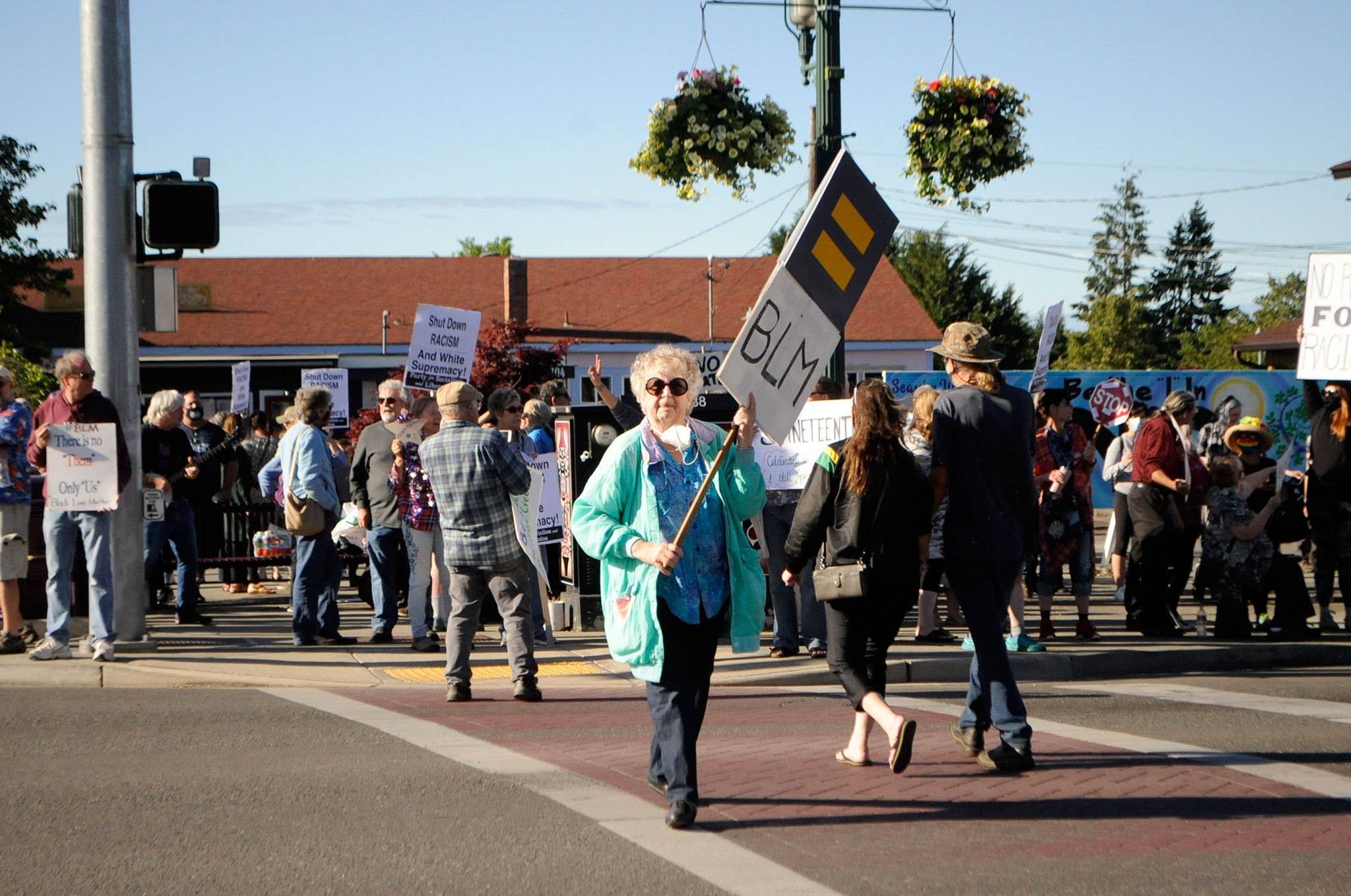 Suzi Morris of Sequim walks with a sign during a protest on Saturday in downtown Sequim recognizing Juneteenth, and condemning racism. “We need keep sharing the message, that’s what we can do,” she said. “We can’t be quiet because that’s just supporting it.” Sequim Gazette photo by Matthew Nash