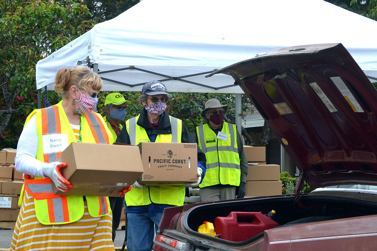 Volunteers Nancy Elwert and Bruce Leigh with Community Emergency Response Teams (CERT) ready to place food boxes in a trunk at Sequim High School in June 2020. Sequim Gazette file photo by Matthew Nash