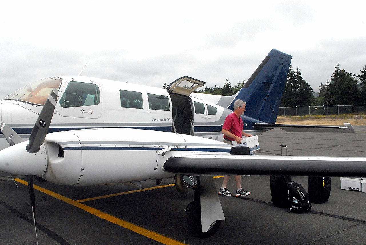 Aspiring Dash pilot Josh Crabtree of Port Angeles unloads boxes of maintenance records from a Dash Air Shuttle Cessna 402C on Wednesday, June 30, at William R. Fairchild International Airport in Port Angeles. Photo by Keith Thorpe/Olympic Peninsula News Group