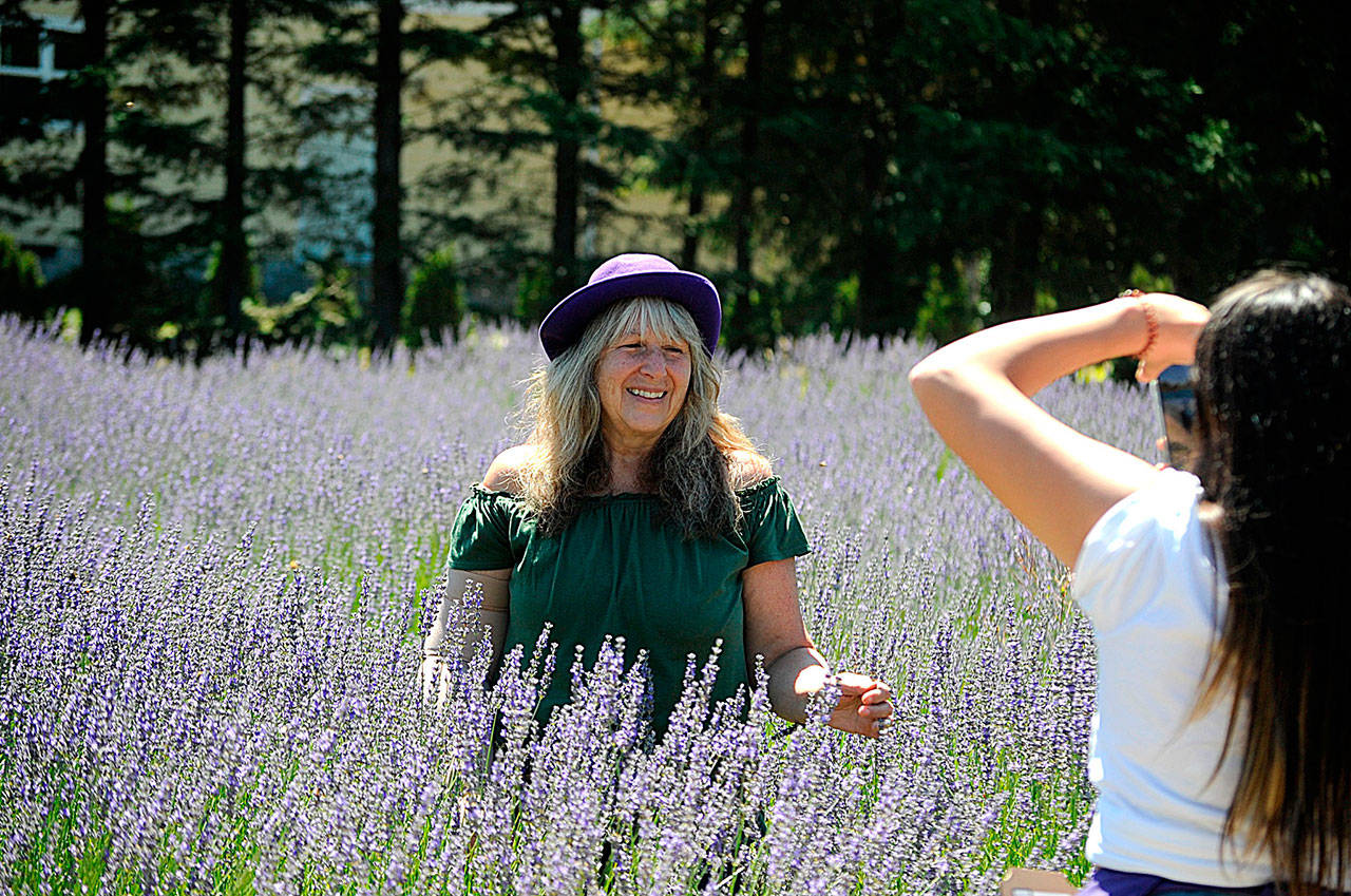 Marilee Entz of Sequim stands in a lavender field at Fleurish of Lost Mountain for a photo-op on July 18 with Ashley Miller taking the photo. Entz helped visitors make lavender wands throughout Sequim Lavender Weekend, she said. Sequim Gazette photo by Matthew Nash