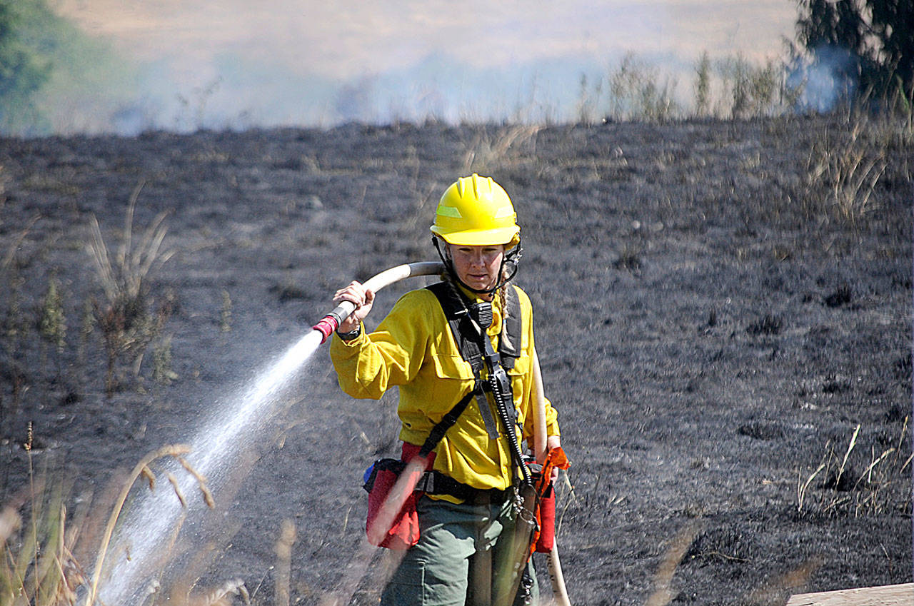 Firefighter/paramedic Margie Brueckner with Clallam County Fire District 2 looks for hot spots at a brush fire near Sherburne Road on Tuesday afternoon. Sequim Gazette photo by Matthew Nash