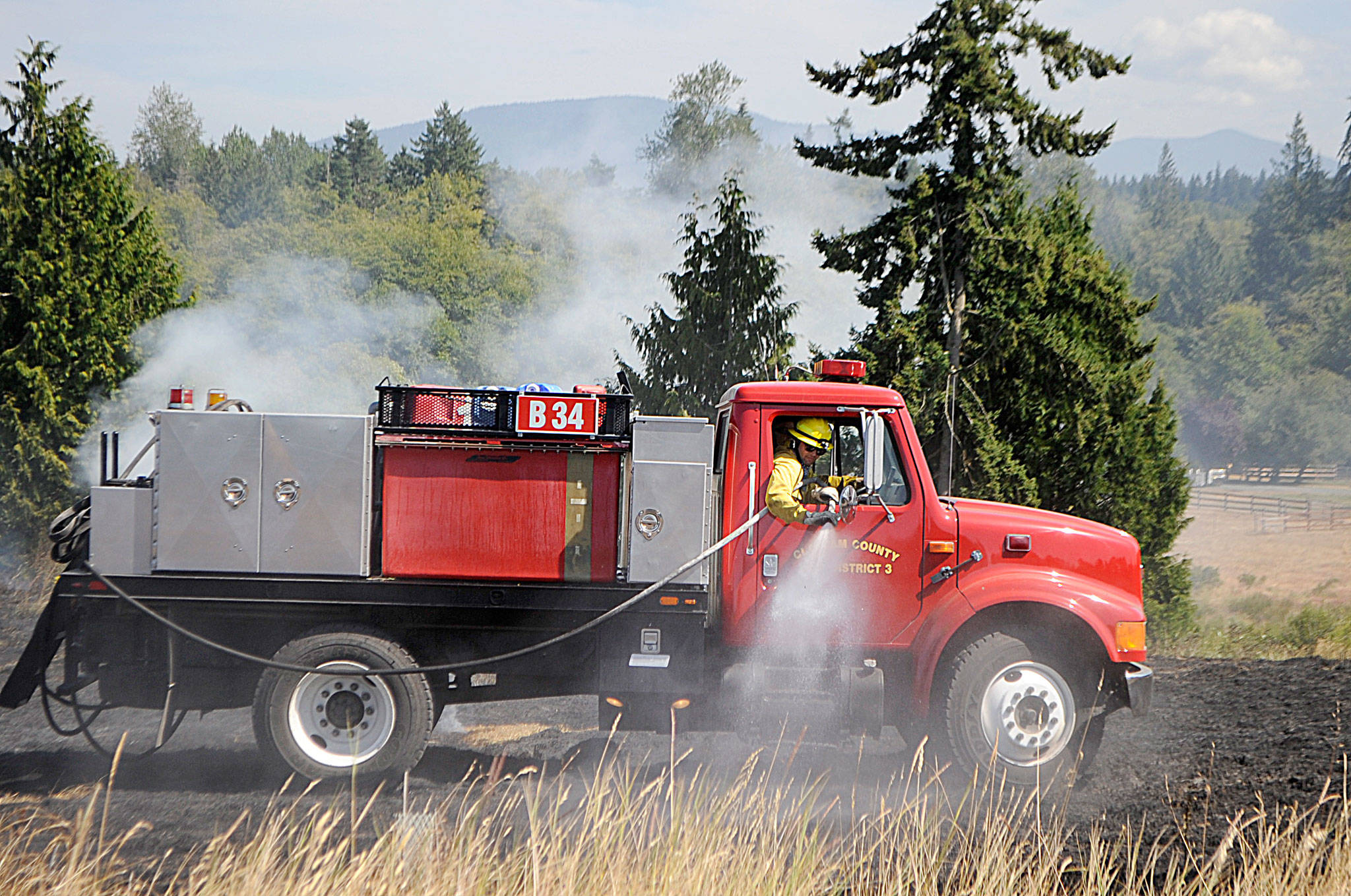 Clallam County Fire District 3 firefighters drive through looking to extinguish any flames on July 27 east of Sequim at a brush fire. Sequim Gazette photos by Matthew Nash