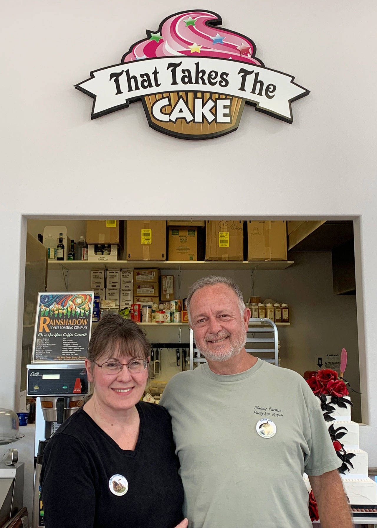 Sue and Paul Boucher of That Takes the Cake in Sequim show off their Olympic Peninsula Tourism Commission “Share” campaign buttons. Photo courtesy of Olympic Peninsula Tourism Commission