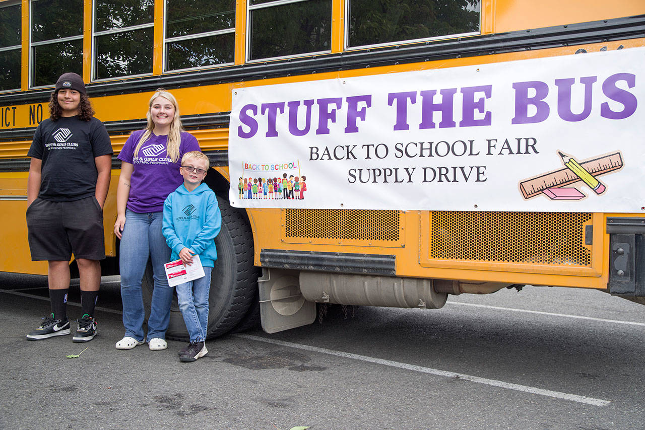 Boys and Girl’s Club Staff Saul Williams and Camryn Wallen with member volunteer Dallton Wilkinson stand outside the Stuff the Bus bus near Office Depot in Sequim on Aug. 6. Williams says he has been helping at this event for seven years. Sequim Gazette photo by Emily Matthiessen