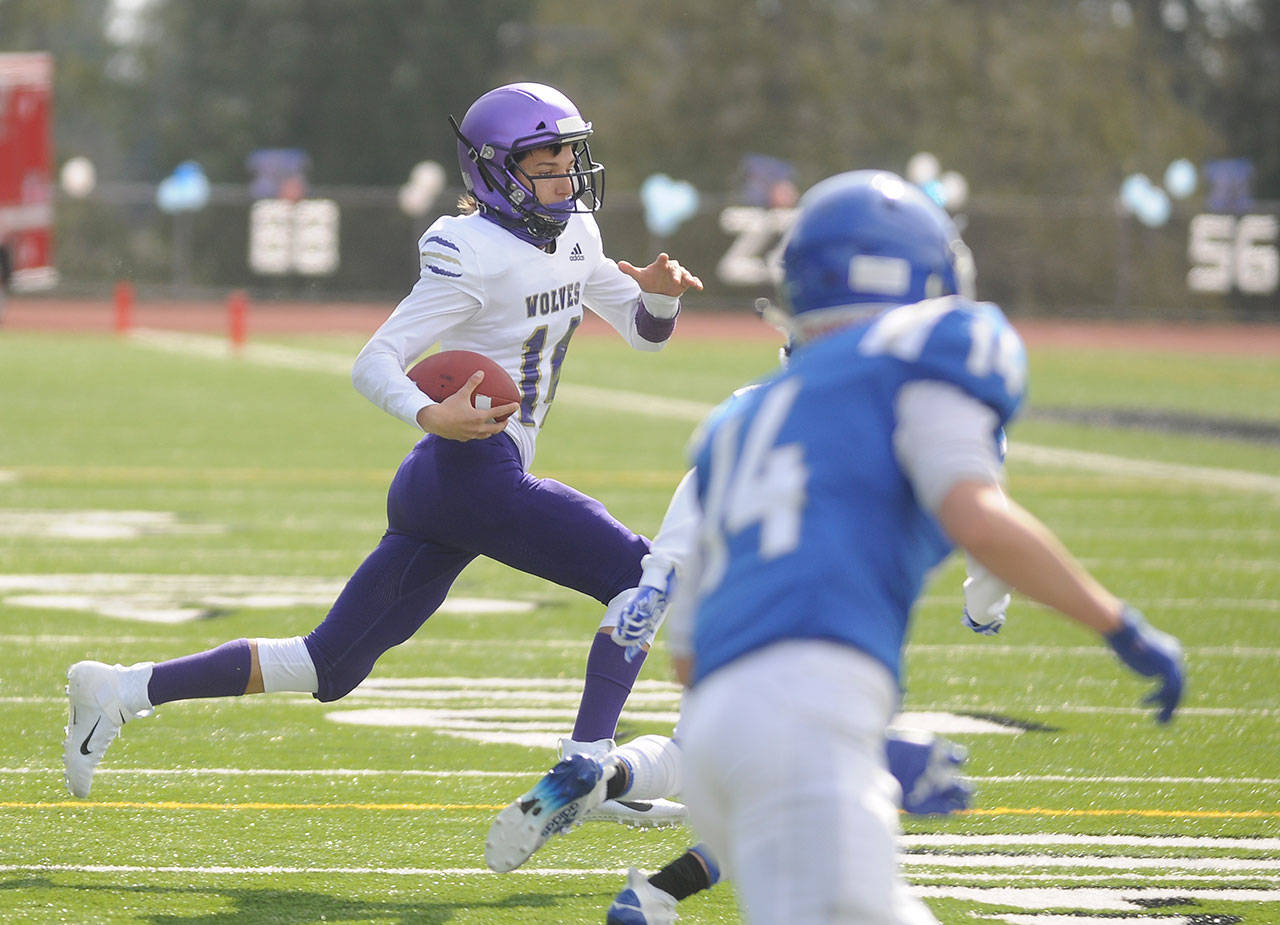 Sequim quarterback Kobe Applegate races for yardage as Sequim High School’s football team takes on Olympic in Silverdale on March 13. The Wolves kick off their 2021 season this week with a first practice on Aug. 18. Sequim Gazette file photo by Michael Dashiell
