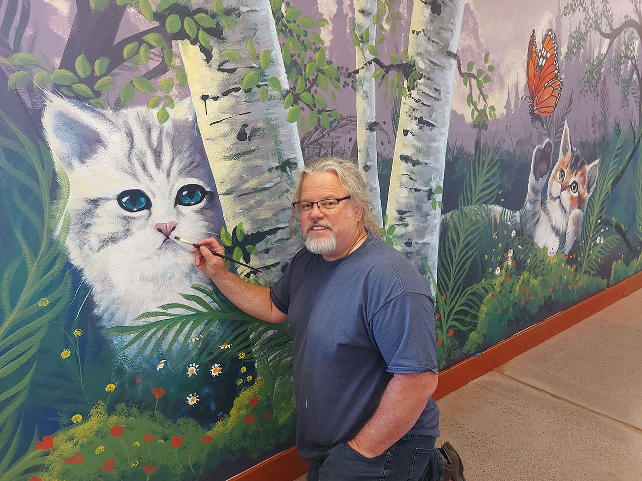 Port Angeles artist Dave Montague works on a mural at the Olympic Peninsula Humane Society’s McKay Kitty City near Sequim. “When I heard about the new Kitty City building, I really wanted to help,” Montague said. “I decided to offer my services to create a mural to capture the cats’ personalities that will live there until adopted. Since I am an avid hiker, I wanted to depict our furry friends in the scenes I have enjoyed through my 3,000 miles of hiking throughout the Olympic Mountains.” Photo courtesy of Olympic Peninsula Humane Society