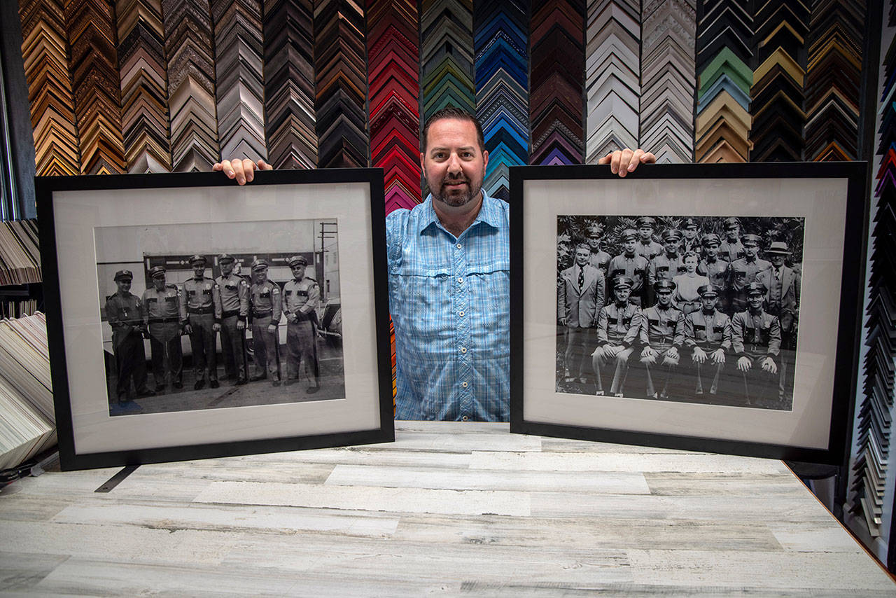 Damon Stamoolis of Sequim’s Clear Image Custom Framing and Photo holds up two of the historic images he digitally cleaned, printed, and framed for the Port Angeles Police Department. Sequim Gazette photo by Emily Matthiessen