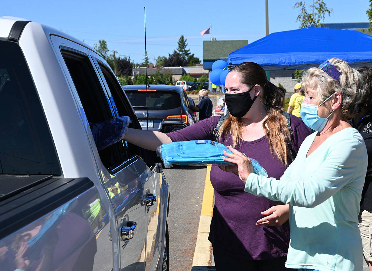 Above: Rachel Tax, left, and Karen Kremkau hand out backpacks at the Back to School Fair at Helen Haller Elementary on Aug. 28. 
At left: Heather Baker, art room director at the Sequim Boys & Girls Club, greets attendees and hands out supplies at the 2021 Back to School Fair.