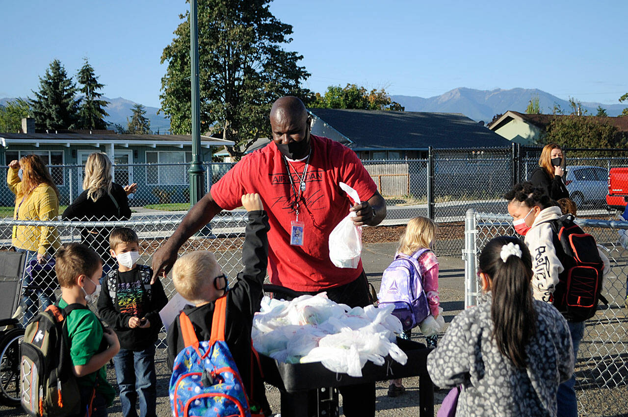 Joclin Julmist, physical education teacher at Helen Haller Elementary, hands out breakfasts to students on the first day of school, Sept. 1, as they get off and on buses for both Haller and Greywolf Elementary schools. Sequim Gazette photo by Matthew Nash