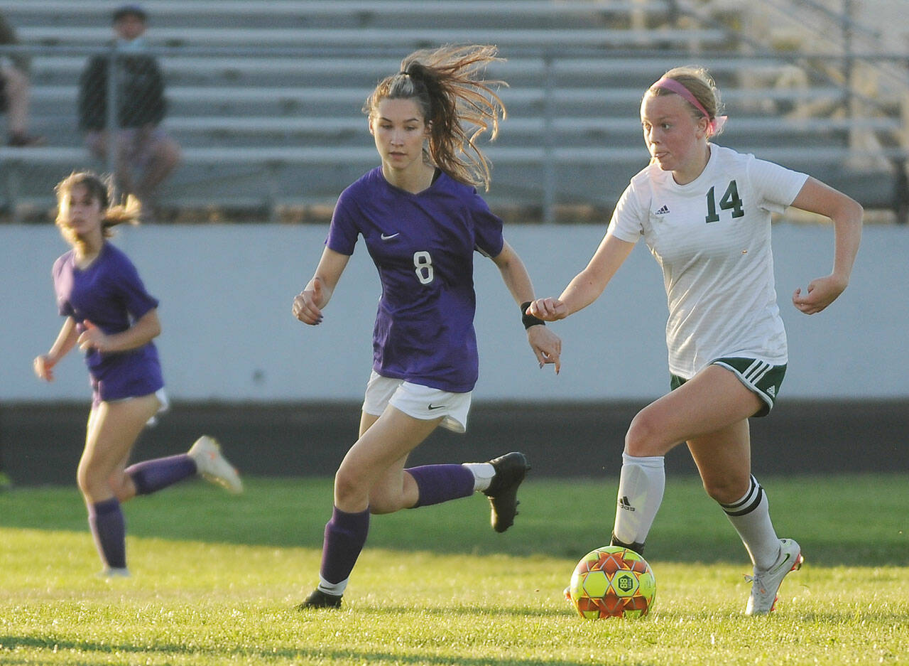 Port Angeles’ Anna Petty left, looks for running room and a teammate as Sequim’s Zoe Moore gives chase in an Olympic League season-opener for both teams on Sept. 9. Sequim Gazette photo by Michael Dashiell