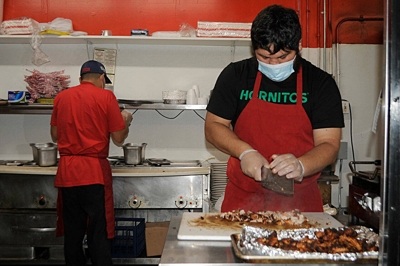Julian Hernandez, right, cuts chicken meat as Jose Garcia preps a meal on Tuesday at Jose’s Famous Salsa. The business was recently highlighted on <a href="https://www.king5.com/article/entertainment/television/programs/evening/joses-famous-salsa-sequim/281-7a5d6069-cf28-4ec1-be01-d25ca4511605" target="_blank">King5’s Evening </a><a href="https://www.king5.com/article/entertainment/television/programs/evening/joses-famous-salsa-sequim/281-7a5d6069-cf28-4ec1-be01-d25ca4511605" target="_blank">program</a>. Sequim Gazette photo by Matthew Nash