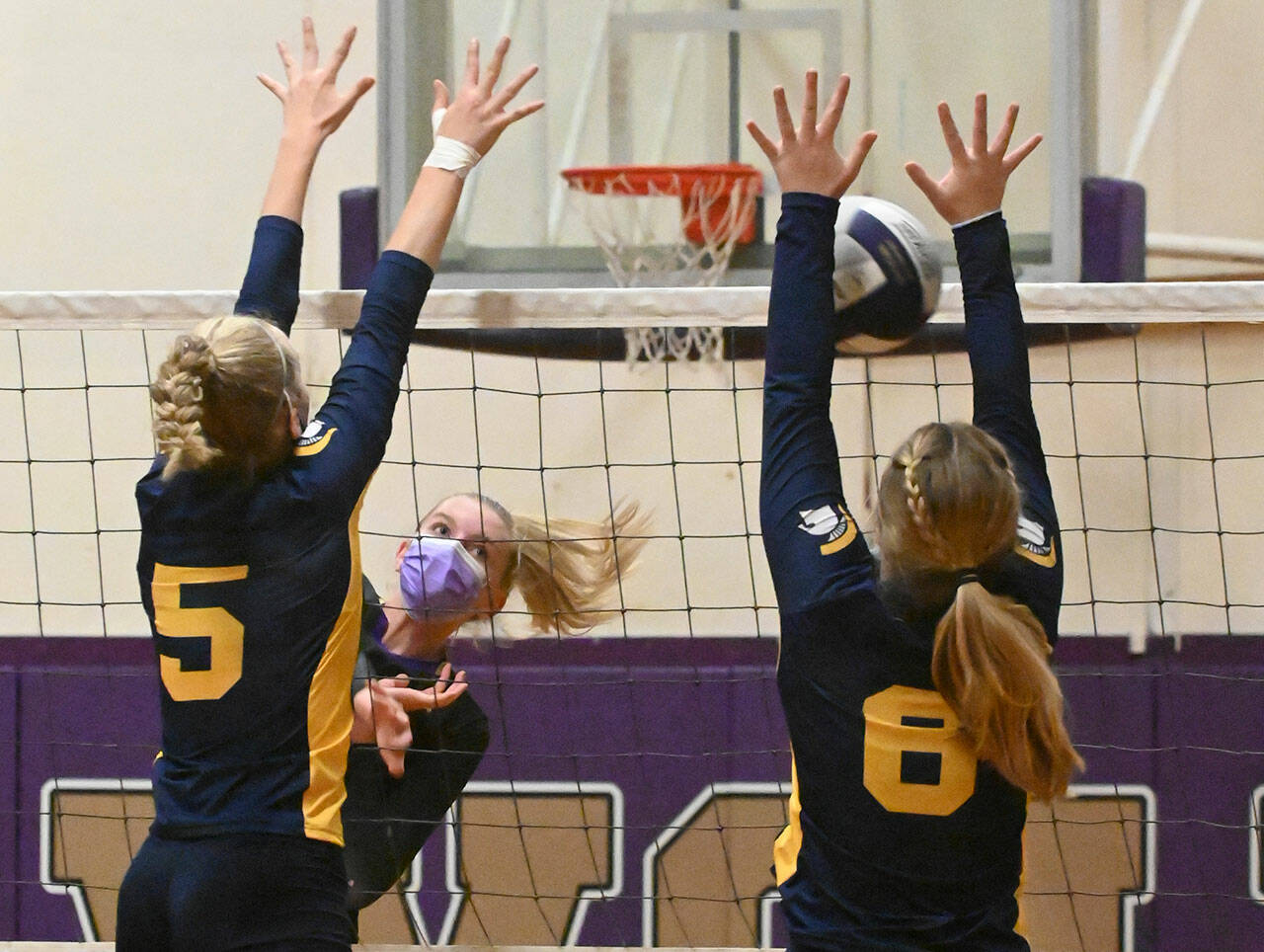 Sequim’s Kendall Hastings, center, looks to hit past the block of Bainbridge’s Izzy Prentice (5) and Scarlett Bos (8) in the Wolves’ 
Sept. 21 home match against Bainbridge.