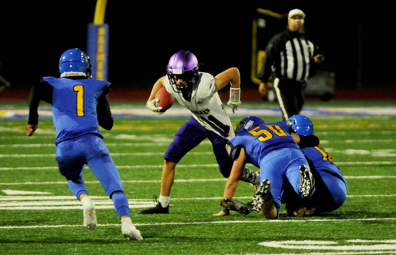 Left: Sequim receiver Kobe Applegate locks in on a pass from Lars Wiker for a 19-yard score in the first half of Sequim’s 35-29 loss at Bremerton on Sept. 30. Above: Sequim’s running back Aiden Gockerell, center, tries to break free from Bremerton defenders (from left) in the first half. Sequim Gazette photos by Michael Dashiell