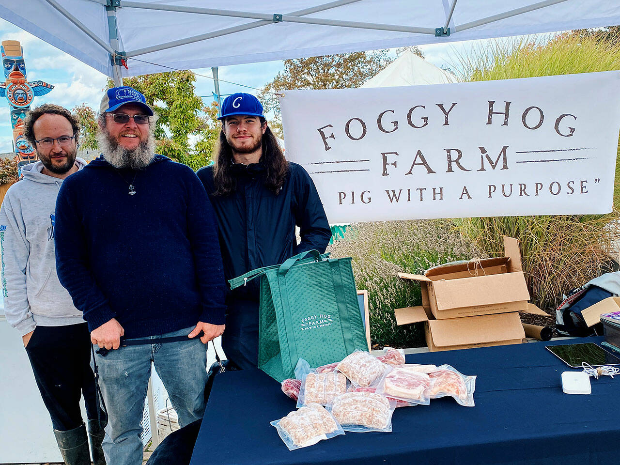 From left, Foggy Hog Farm owner Alex Lemay and crew members Sage Vann and Cole Dotson are ready to greet customers at the Sequim Farmers & Artisans Market Saturday. Photo by Emma Jane Garcia