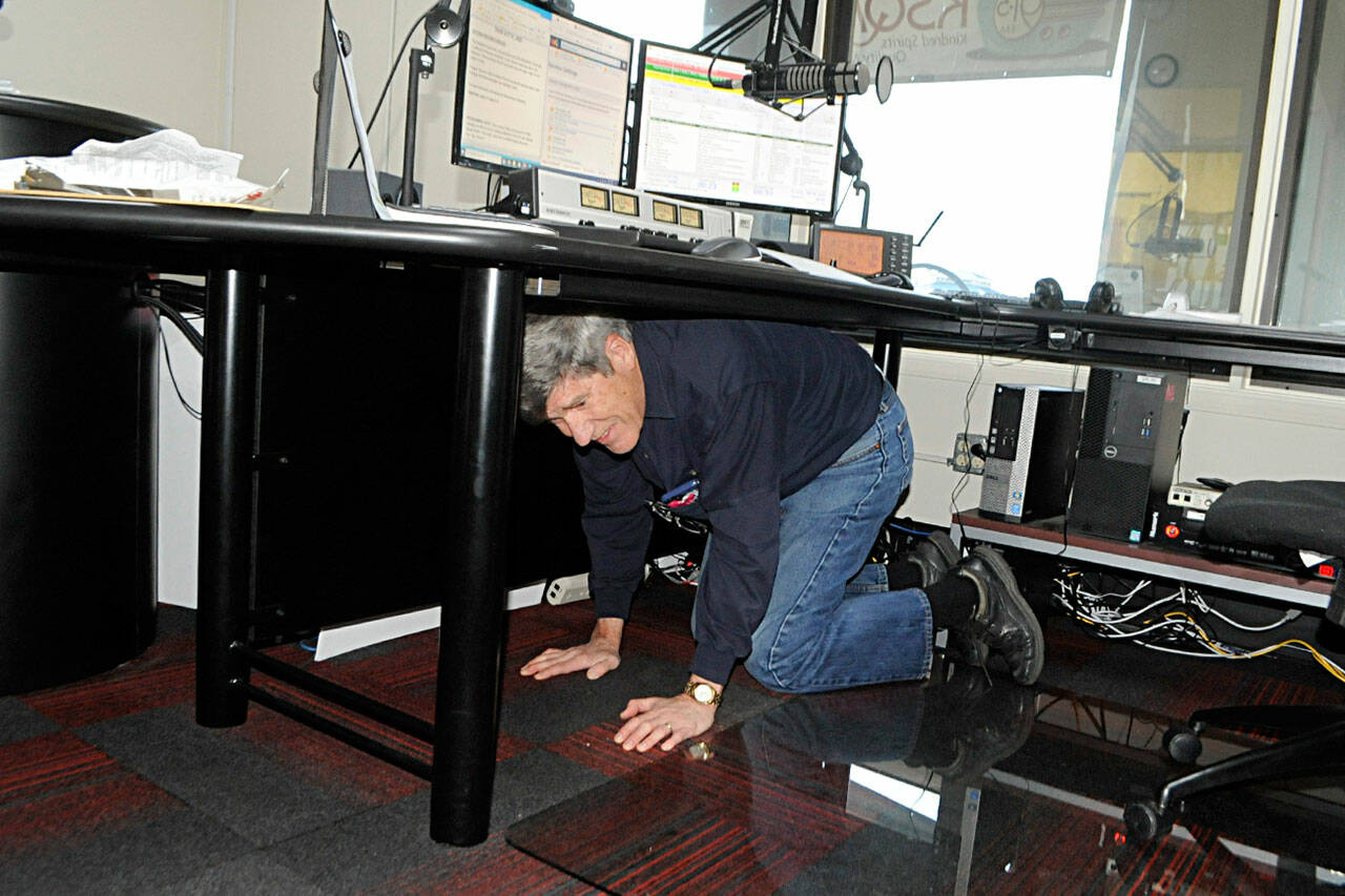 Bud Davies drops and covers during the Great Washington Shakeout drill on Oct. 21. He and about a dozen KSQM volunteers sent the test drill to the airwaves and did a drill themselves to prepare for a potential earthquake or tsunami.