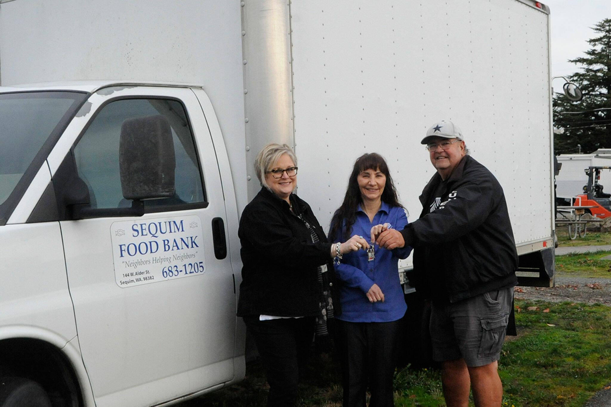 Sequim Food Bank leaders, executive director Andra Smith, on left, and volunteer Stephen Rosales, right, hand the keys of the facility’s longtime delivery truck to Mary Budke, executive director of the Boys & Girls Clubs of the Olympic Peninsula on Nov. 8. Budke said they’ll use it to pickup large donations and transfer items between the Sequim and Port Angeles units. Sequim Gazette photo by Matthew Nash