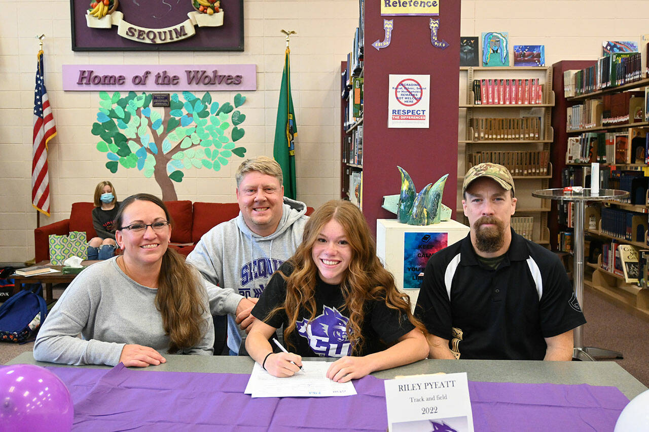 Sequim High senior Riley Pyeatt, pictured here with (from left) mom Tracie, cross country/track coach BJ Schade and dad Doug, signs a letter of intent to compete with the Abilene Christian track team on Nov. 10. Sequim gazette photo by Michael Dashiell