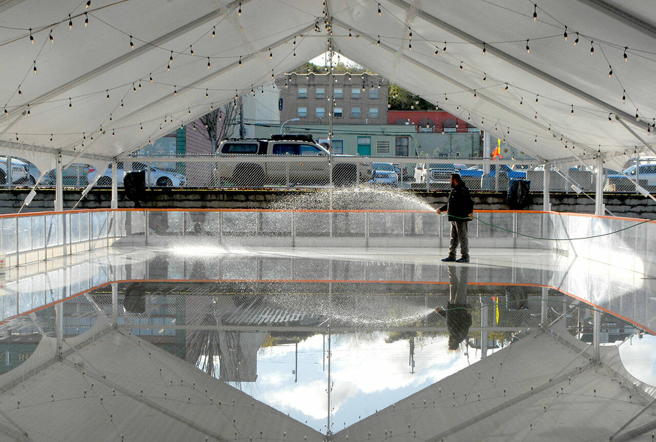 Shawn Kidwell, an employee of Ice-America, a California-based company that rents portable ice rinks, applies water on Tuesday, Nov. 16, to the refrigerated surface of a temporary rink that will be the highlight of the Port Angeles Winter Ice Village. Photo by Keith Thorpe/Olympic Peninsula News Group