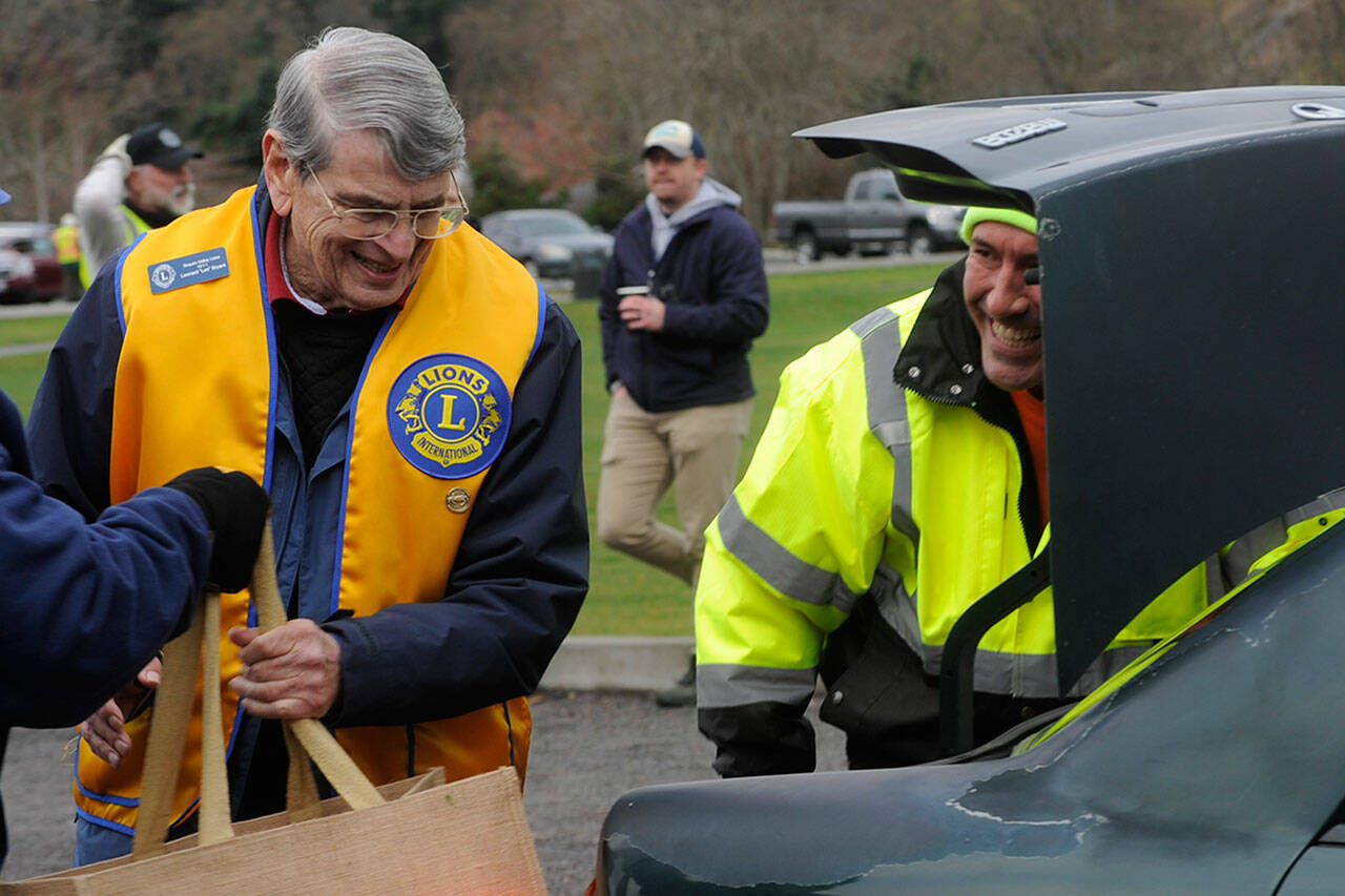 Len Bryant with the Sequim Valley Lions and Lynie Staus work together to load a car with food for the Holiday Meal Food Bag program on Nov. 19 in Carrie Blake Community Park. Staus said he wanted to volunteer because “there isn’t anything better than putting back in your community.” Sequim Gazette photo by Matthew Nash