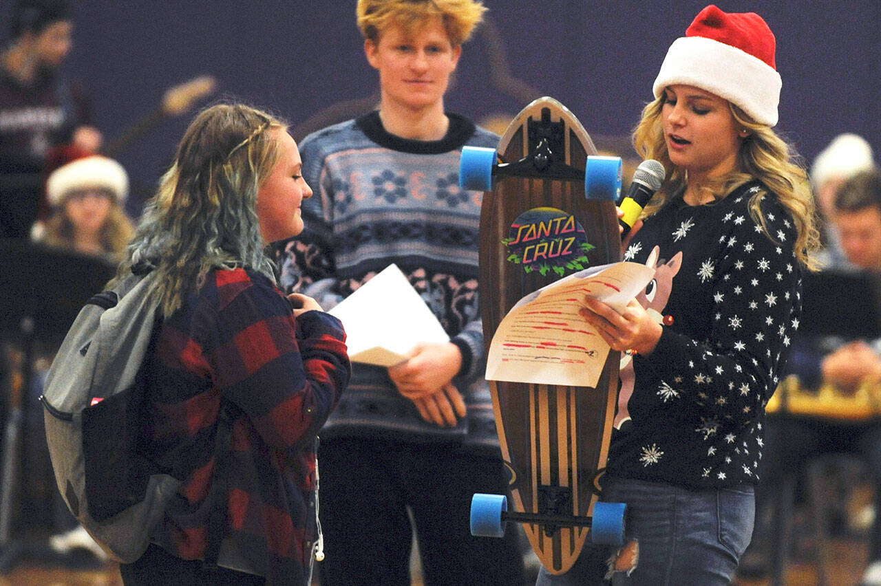 Gretta Thorson, right, presents an SHS student with a skateboard as part of the Sequim High School Winter Wishes assembly in December 2019. Sequim Gazette photo by Conor Dowley