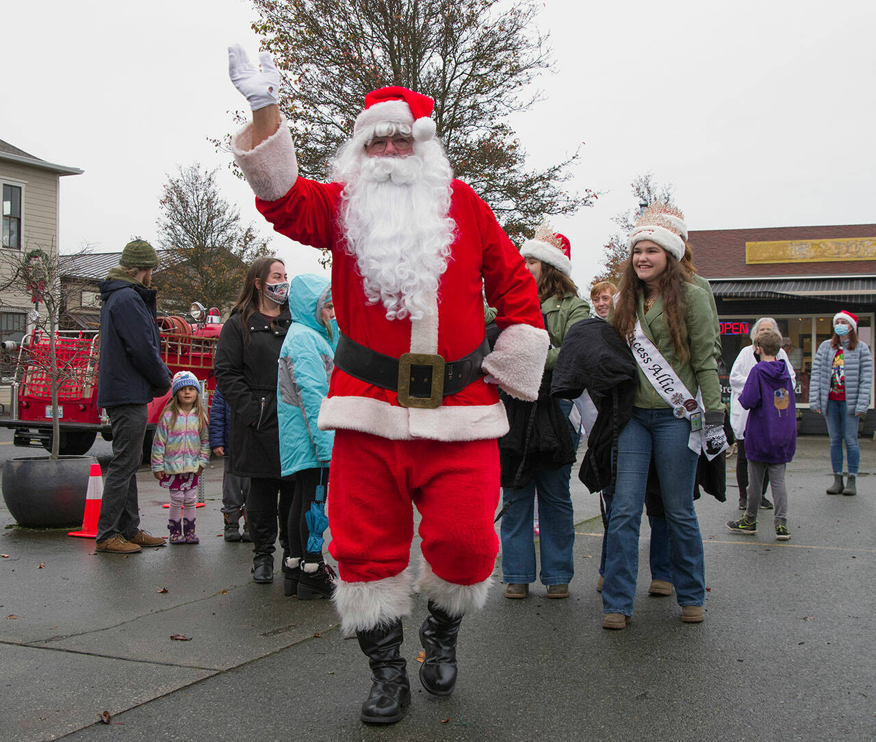 Santa waves at the people in Centennial Square after disembarking an antique firetruck with Sequim Irrigation Festival Royalty. Seen behind him is Princess Allie Gale. Sequim Gazette photo by Emily Matthiessen