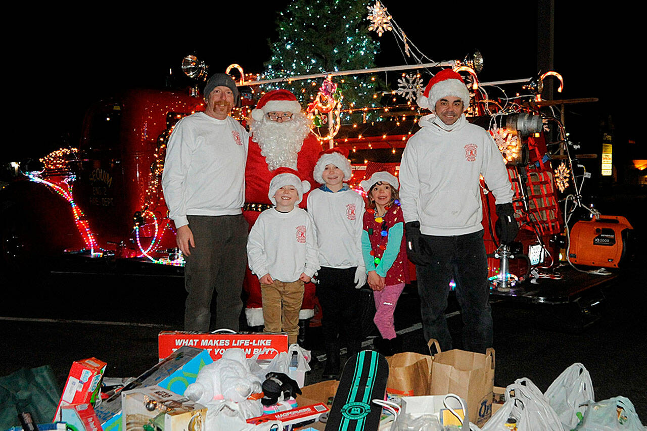 Santa Brigade crew members, from left, Marc Lawson, Santa Claus (John Brygider), Parker Horst, Connor Horst, Isabel Lawson, and Len Horst gather at the end of three days of gathering goods for Toys for Sequim Kids. Sequim Gazette photo by Matthew Nash