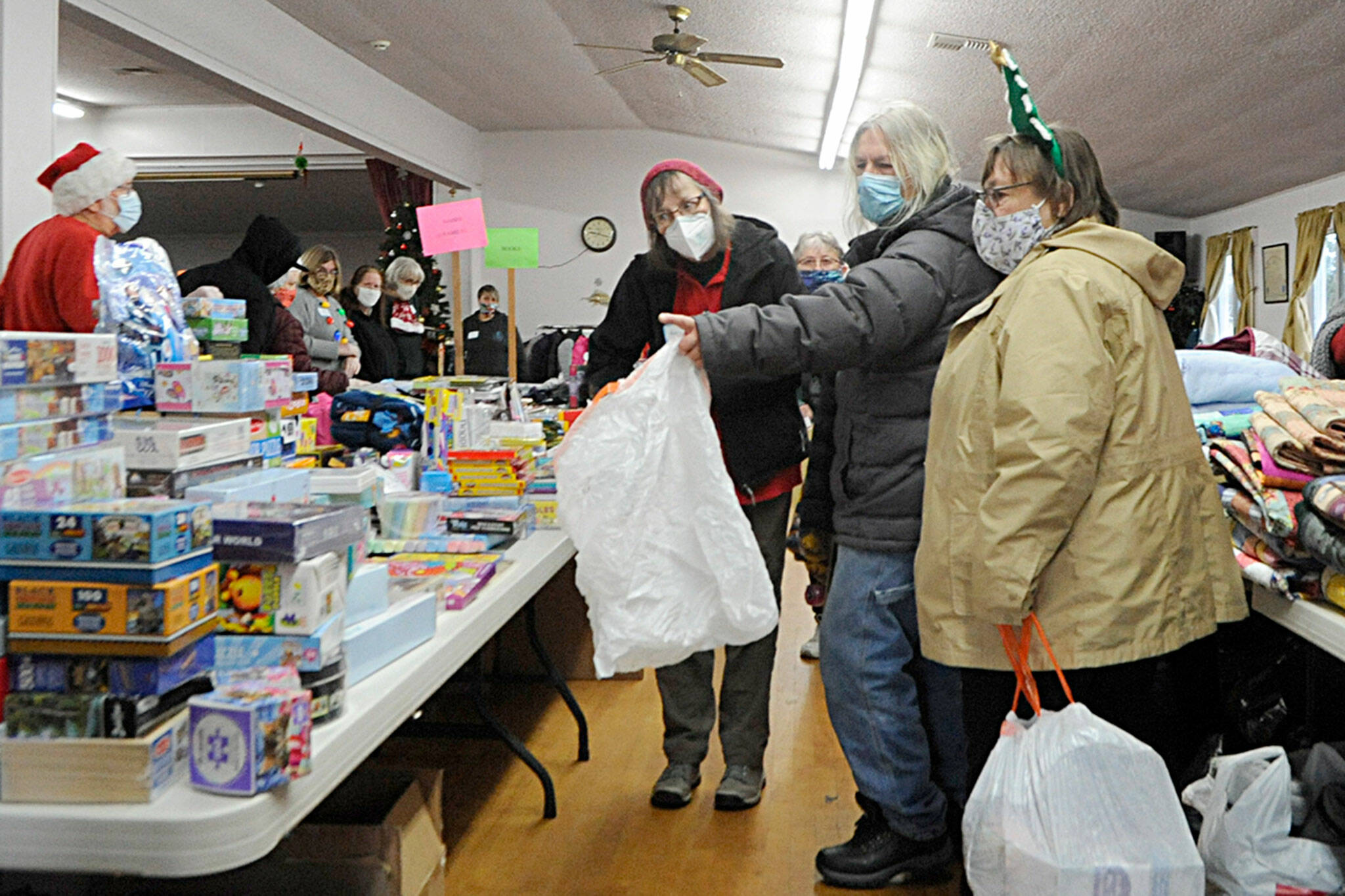 Marion Rutledge and Kathy Downer help John Eddy hunt down the best puzzles and games during Toys for Sequim Kids. Sequim Gazette photo by Matthew Nash