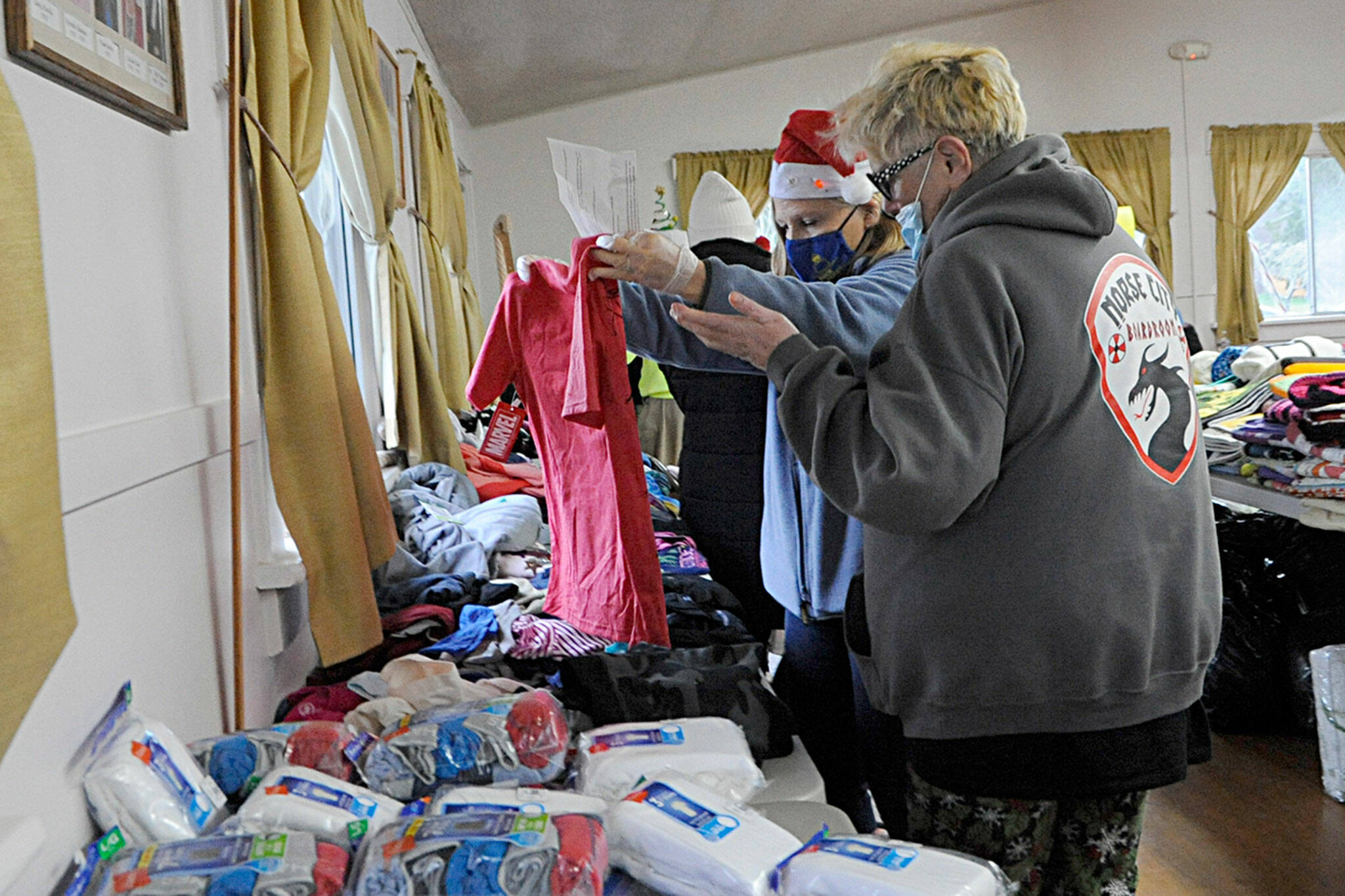 Kathy Joyner, co-organizer of Toys for Sequim Kids, helps Jean Ann Houk size up a t-shirt for one of her children this Christmas. Sequim Gazette photo by Matthew Nash