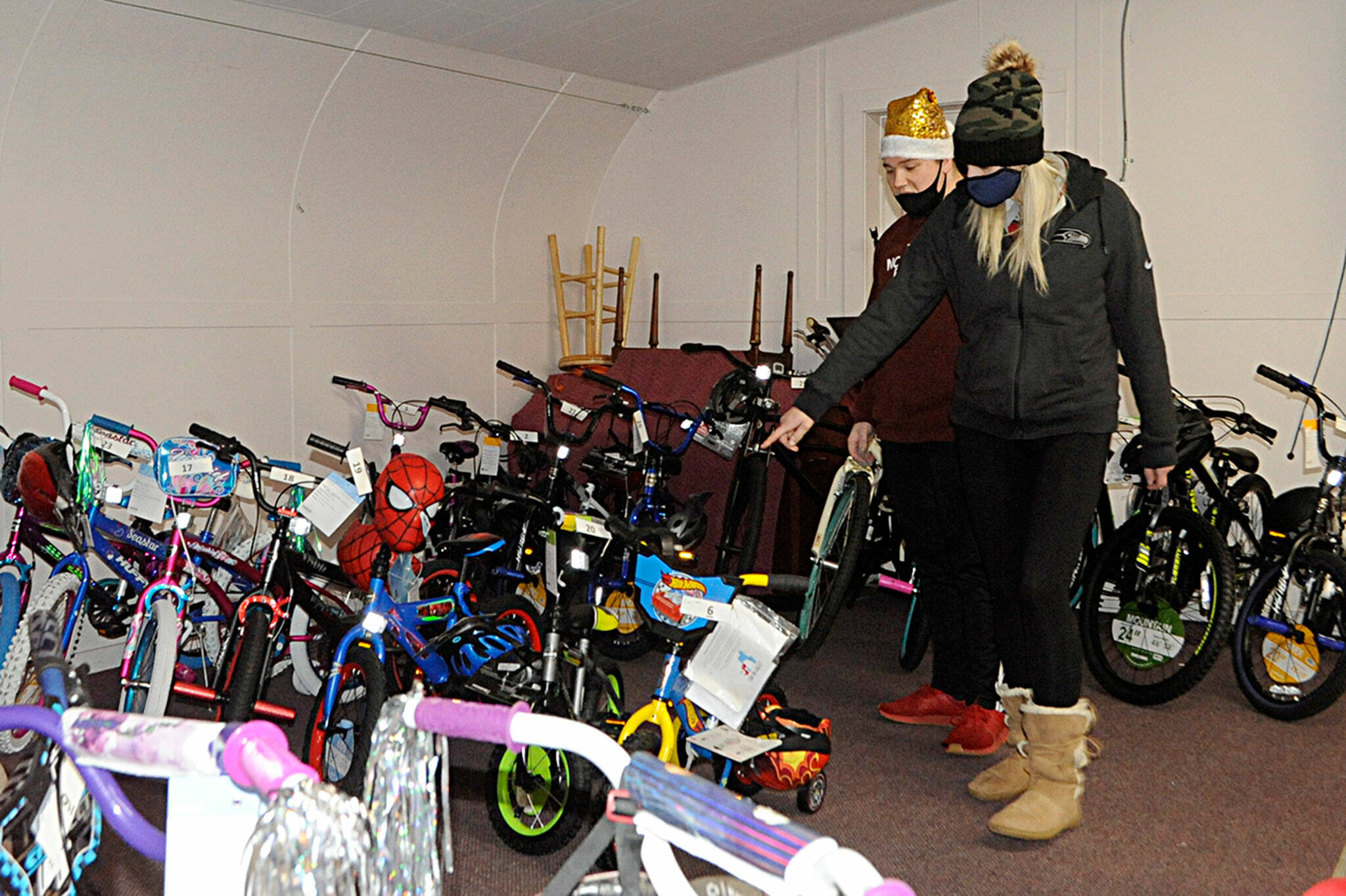 Brandy Brogan picks a bike out at Toys for Sequim Kids with help from volunteer Ryan Cherry, a Church of Jesus Christ of Latter-day Saints missionary, for a chance to receive one of 34 bikes in Sequim Community Aid’s raffle. Sequim Gazette photo by Matthew Nash