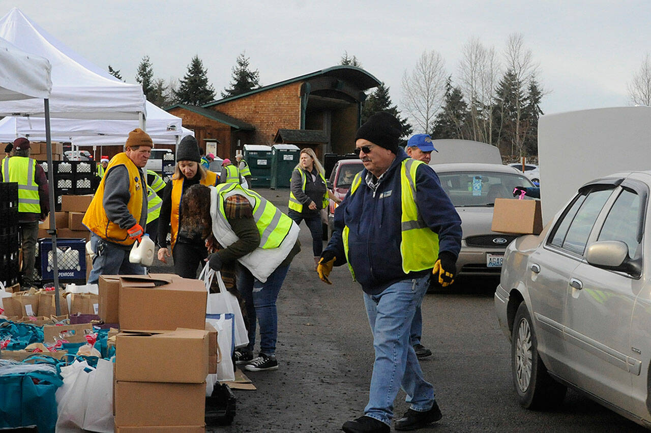 Several volunteer groups work together to load vehicles with food for the holidays during the Family Holiday Meal Bag program on Dec. 17 in Carrie Blake Community Park. Sequim Gazette photo by Matthew Nash
