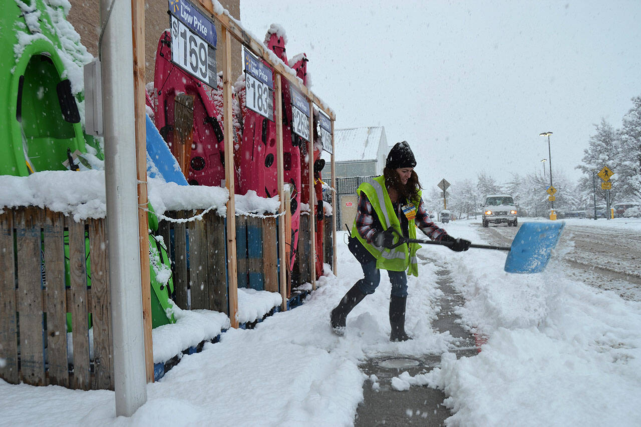 Jeni Madsen, manager of boys and men clothing at Sequim Walmart, helps shovel a pathway in February 2019 as snow begin to blanket the area. City crews are preparing for the possibility of snowfall this weekend. Sequim Gazette file photo by Matthew Nash