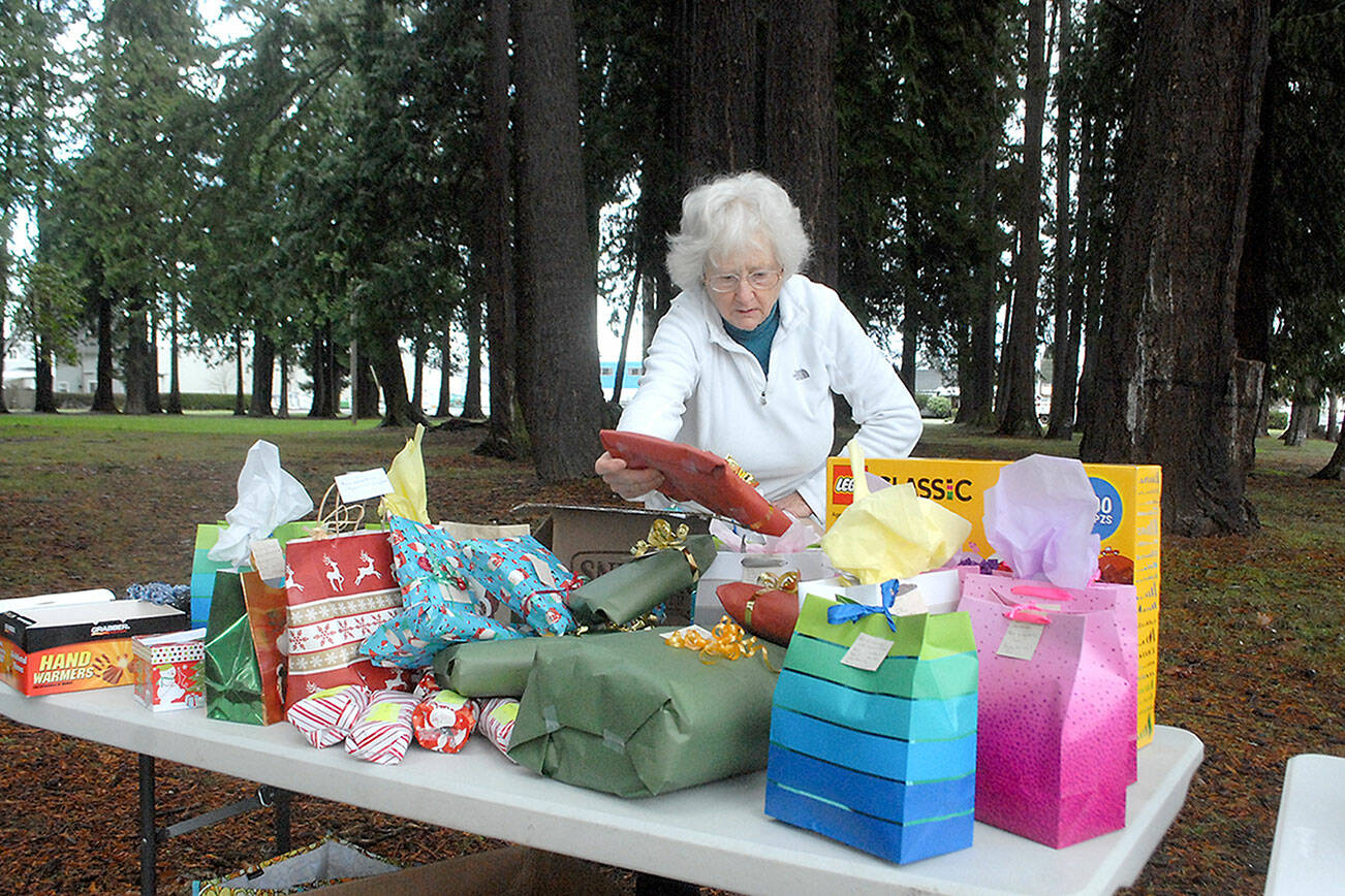 Keith Thorpe/Peninsula Daily News
Ingrid Carmean of Port Angeles, a member of Food Not Bombs, an international group dedicated to assisting and feeding homeless individuals, sets up a table filled with Christmas presents on Saturday at Jesse Webster Park in Port Angeles.  The presents, along with a hot lunch, were distributed to needy individuals on Christmas Day, one of the group's every-other-weekend community meals.