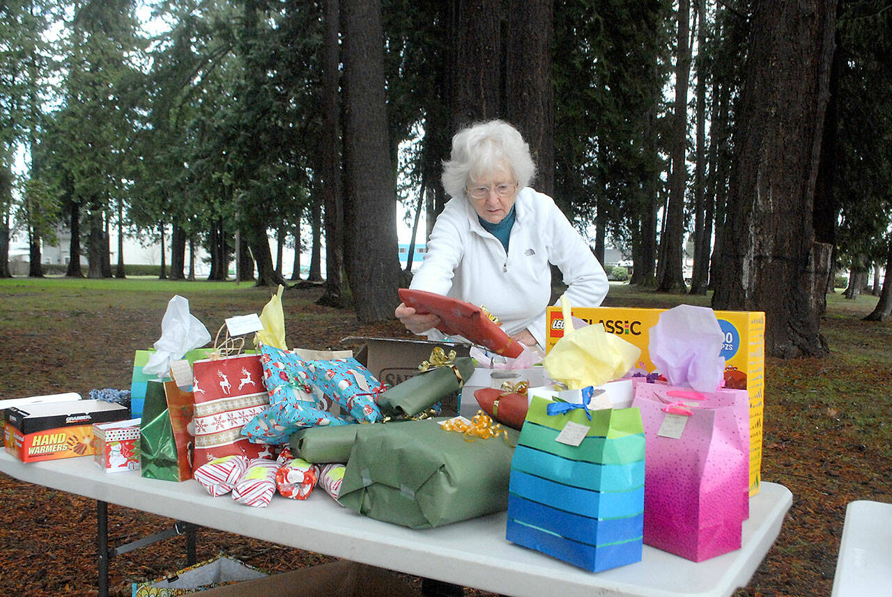 Ingrid Carmean of Port Angeles, a member of Food Not Bombs, an international group dedicated to assisting and feeding homeless individuals, sets up a table filled with Christmas presents on Dec. 25 at Jesse Webster Park in Port Angeles. The presents, along with a hot lunch, were distributed to needy individuals on Christmas Day, one of the group’s every-other-weekend community meals. Photo by Keith Thorpe/Olympic Peninsula News Group