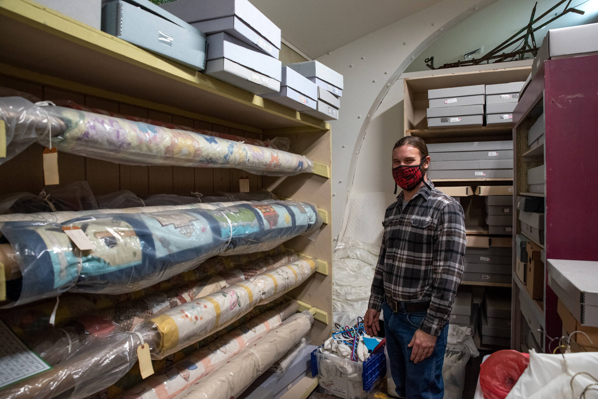David Brownell, North Olympic History Center Executive Director, stands near rolls of heirloom quilts sewn by ancestors on the peninsula.