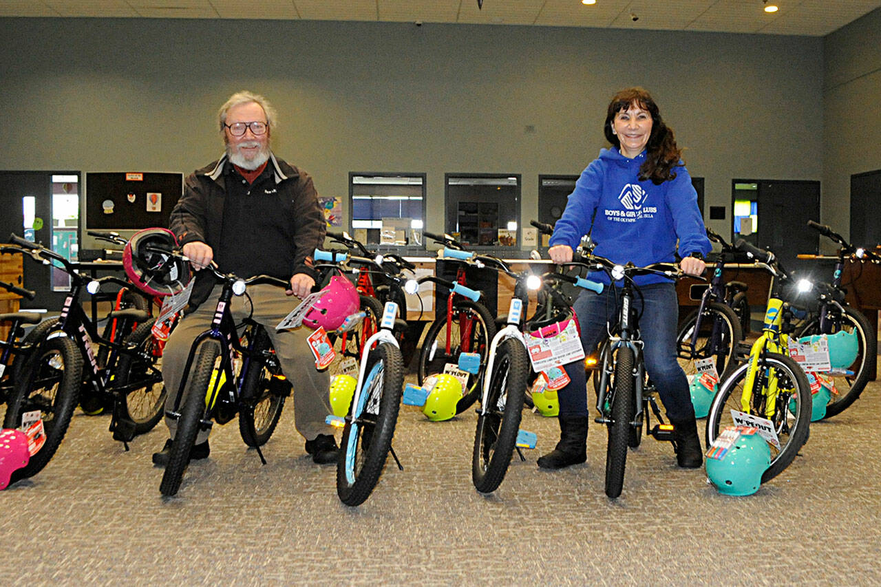 Sam Chandler, owner of Ben’s Bikes, and Mary Budke, executive director of the Boys & Girls Clubs of the Olympic Peninsula, sit on some new bikes Chandler donated for in-need club members in Sequim and Port Angeles.