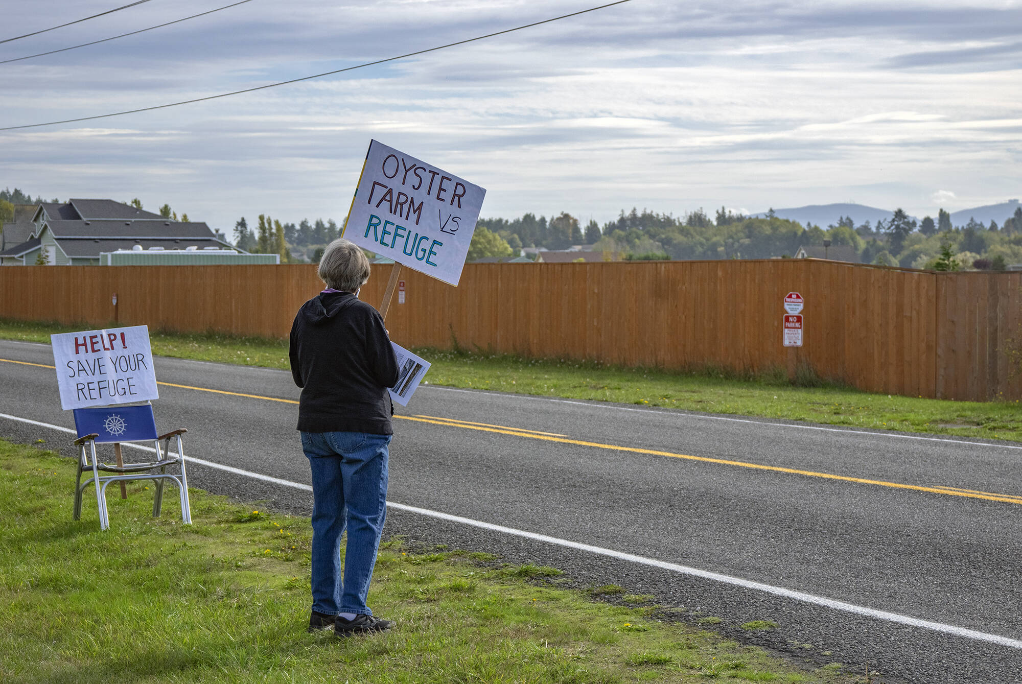 Janet Marx of Protect the Peninsula’s Future waits on the edge of Lotzgesell Road in Sequim to share information with people entering the Dungeness Wildlife Refuge about a planned oyster farm at the refuge in October 2021. Sequim gazette photo by Emily Matthiessen