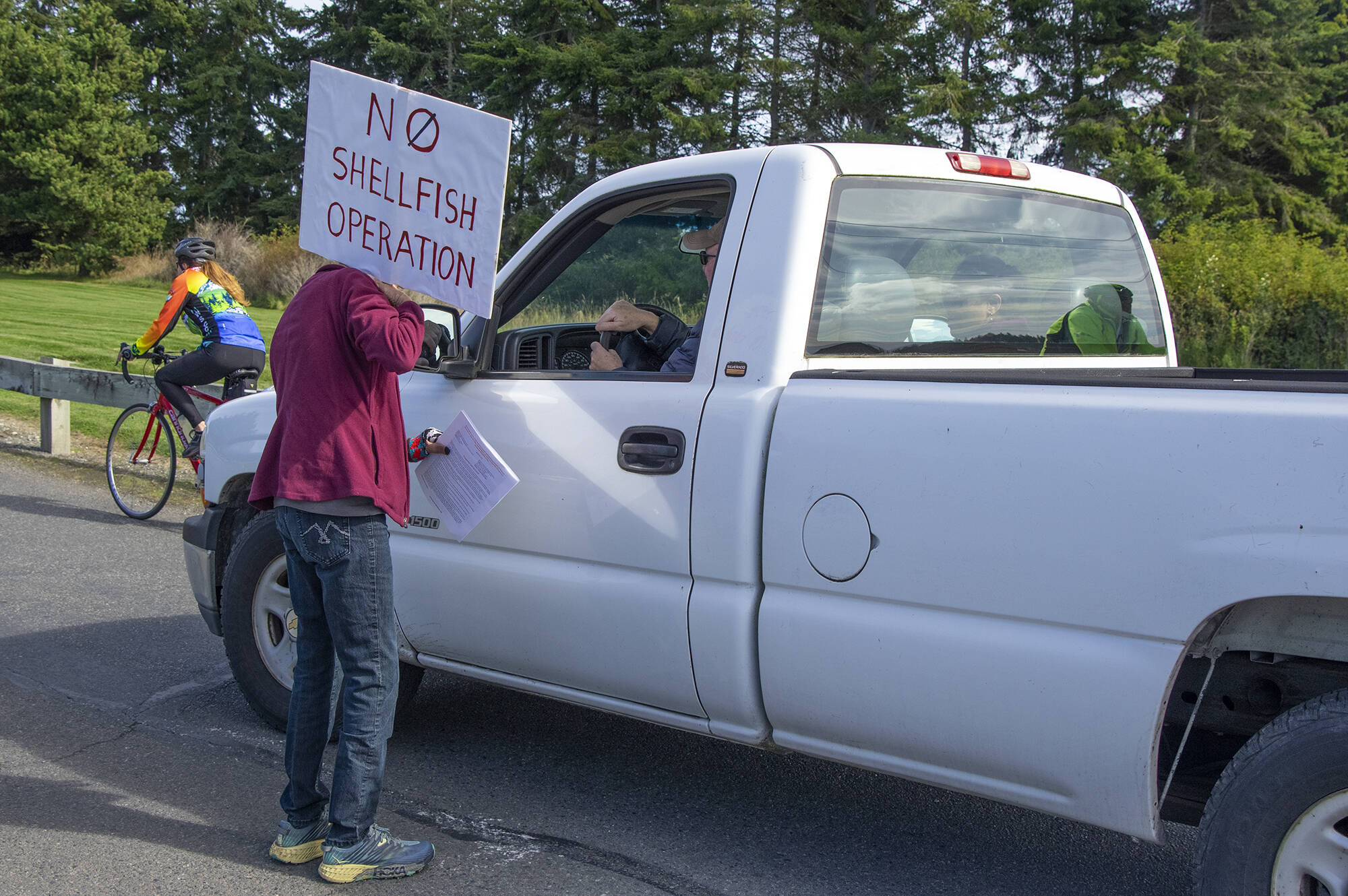Jane Erickson speaks with a drive entering the Dungeness National Wildlife Refuge on Oct. 2, 2021, during a protest against a future oyster farm at the refuge in Sequim. Sequim Gazette photo by Emily Matthiessen