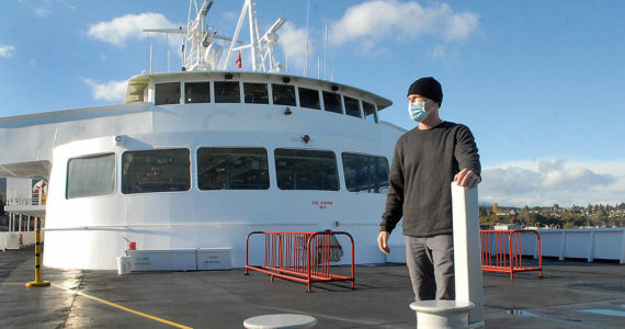 Rian Anderson, Port Angeles district manager for Black Ball Ferry Line, stands on the forward deck of the MV Coho, which will resume daily journeys across the Strait of Juan de Fuca today, 20 months after it was docked by international border restrictions due to COVID-19. The Port Angeles Chamber of Commerce plans a small send-off when it leaves for its first run at 8:20 a.m. and a large welcome of Canadians, who have sold out the ferry, at noon at the ferry terminal. (Keith Thorpe/Peninsula Daily News)