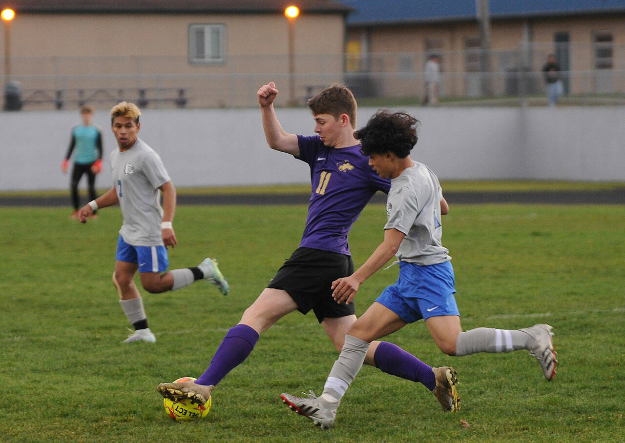 Sequim’s Ethan Knight, center, looks for an open teammate in the Wolves’ 4-0 home win over North Mason on March 15. Knight scored the Wolves’ first goal of the season in the 45th minute.