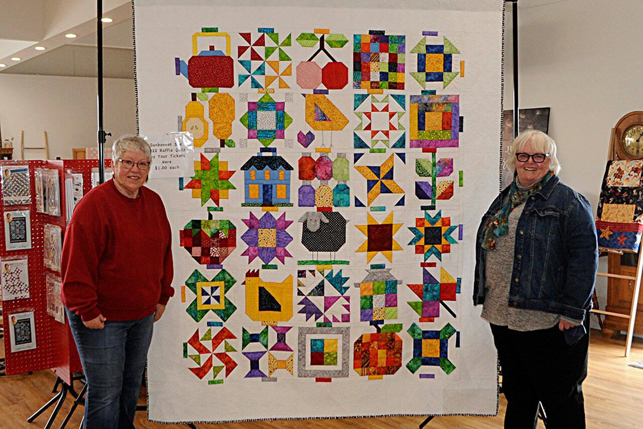 Sequim Gazette photo by Matthew Nash/ Members of the Sunbonnet Sue Quilt Club bring their annual raffle quilt “Down on the Farm” to the Sequim Museum and Arts on April 1 to start promotions for their annual show set for July 16 in Pioneer Memorial Park. Bonnie Filgo, left, pieced the quilt together, and Marianne Nolte, club president, looks to sell out of raffle tickets before the show.