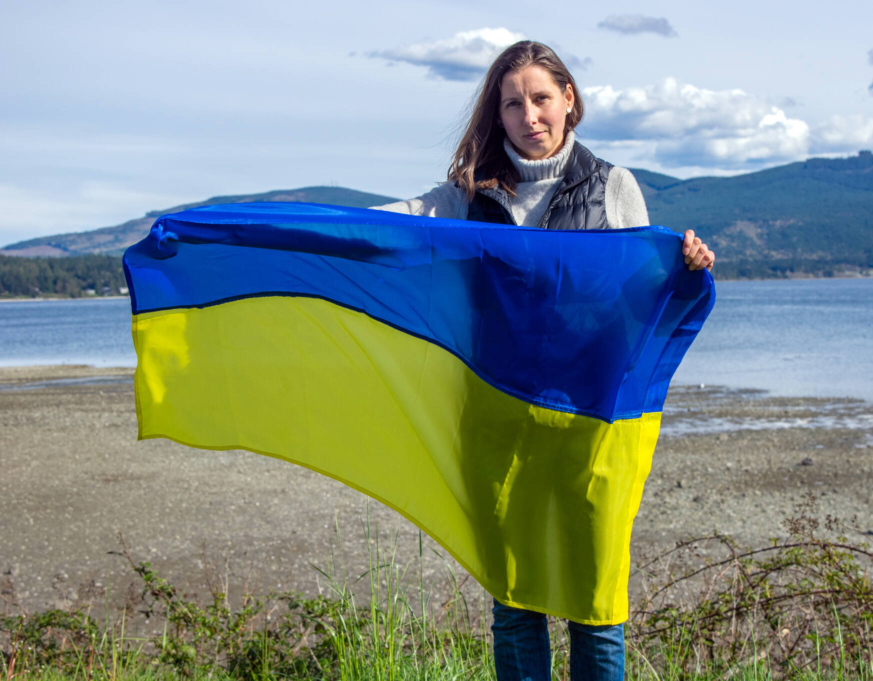 Ukrainian-American Mariia Bush holds the Ukrainian flag up at the John Wayne Marina in Sequim as she discusses the upcoming “Ukraine at the Table” benefit to be held at Bella Italia on Tuesday, April 19. Sequim Gazette photo by Emily Matthiessen